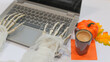 © Julia_Ro - Skeleton Hands Typing on Laptop with Coffee Cup,Pumpikn, autumn leaves, Halloween Work Concept. side view