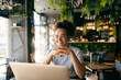 © Dusan Petkovic - Cheerful remote worker sitting in cafe and smiling at the laptop.