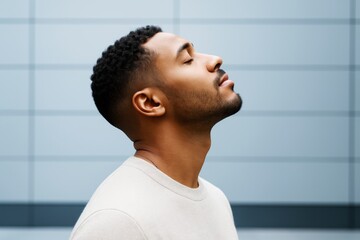 Aufkleber - Peaceful young man with eyes closed standing in profile against modern blue background, embracing serenity and mindfulness concept outdoors.
