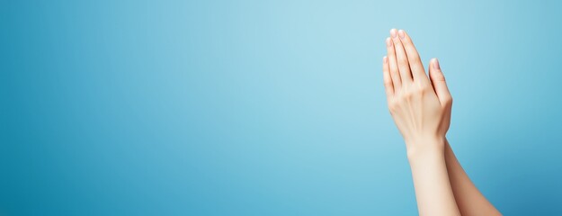 Poster - Female hands pressed together in prayer gesture on clean blue background with copyspace for design, wellness, culture, or creative promotion concepts.
