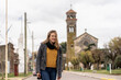 © lucegrafiar - Woman standing on quiet street with historic church behind