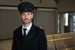 © Wavebreak Media - Mature male pilot standing near seats in airport lounge wearing peaked cap with striped epaulets