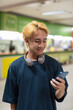© Ranta Images - Young Asian tourist man in bus station using phone