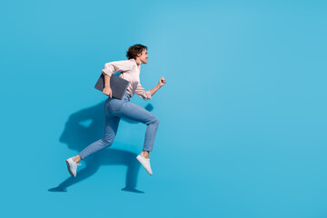 Poster - Young businesswoman in pink satin blouse running against blue background with laptop in hand, showcasing elegance and confidence