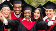 © Prostock-studio - Happy multiracial group of students in graduation dresses and hats taking selfie together, posing at university campus, enjoying and celebrating graduation, closeup portrait