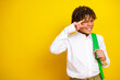 © deagreez - Smiling boy making a hand gesture while holding a green strap against a bright yellow background