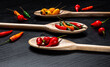 © BY BRAZIL - Various types of peppers in wooden spoons on a black background. Top view.
