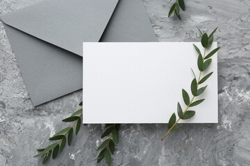 Wall Mural - Blank invitation card, branches and envelope on grey textured table, flat lay. Space for text