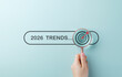 © Sandwish - Searching Business Trends for 2026. A hand holding magnifying glass over search bar 2026 Trends, symbolizing trend forecasting, marketing, new ideas, strategic plan in new year, business predictions,