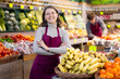 © JackF - Young woman seller in apron lays out bananas on counter in vegetable shop