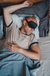 © Soloviova Liudmyla - Portrait of middle aged bald man with short beard wearing black sleeping mask lying comfortably in bed during early morning promoting healthy restful lifestyle.