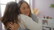 © Krakenimages.com - Mother and daughter embrace lovingly in a cozy living room, capturing a moment of family affection indoors.