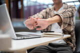 Close up of plaid shirt man stretching his hands over laptop with notebook aside sits at cafe table.