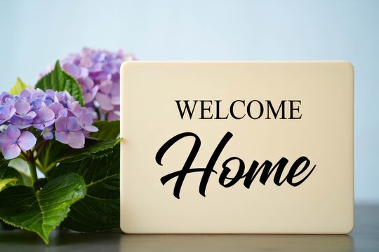 Welcome Home text with flowers decoration on light blue background.