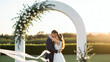© galam - Couple de mariés sous une arche fleurie