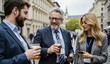 © jiale - Three professionals engaged in conversation while holding drinks on a city street.