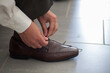 © Bjorn B - A welldressed gentleman adjusts his polished brown shoe, highlighting attention to detail in his formal wear
