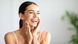 © saokaew - Beautiful woman smiling and laughing with joyful energy while touching her skin in a bright and positive atmosphere