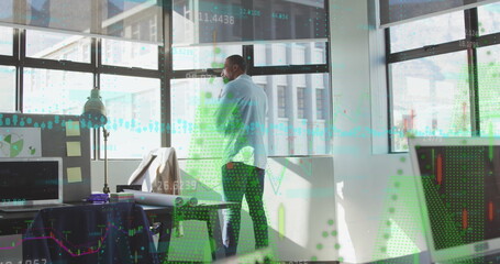 Poster - Talking businessman holding smartphone while gazing outside in modern office with chart overlays