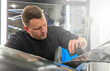© Dmitry Presnyakov - A car wrapping specialist applies a matte polyurethane film to the car. Selective focus. PPF protective film against chips and scratches. Car wrapping. Wrapping protective film on the car.