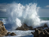 Powerful ocean waves crash on coastal rocks, sending sea spray high into the stormy sky