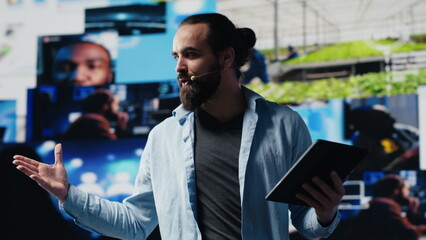 Poster - Male cool IT expert hosting a live convention with hands free microphone, engaging an audience from the stage to discuss social media reach and digital interaction. Communication. Camera A.