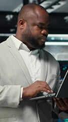Poster - Vertical video Technician walking in data center, using laptop to check hardware for system stability. Worker overseeing server farm, using notebook to configure infrastructure, optimizing performance