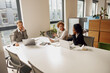 © Yaroslav Astakhov - Three professional women are having a productive discussion at a conference table in a modern office