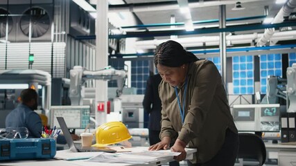 Poster - african american female expert reviewing solar panels production line, doing quality control in a ph