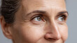 © Marut - Closeup of mature woman face showing natural skin texture with wrinkles and fine lines around eyes and nose, expressing calm and thoughtful emotion