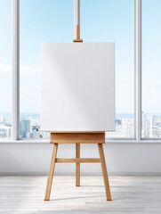 Poster - Blank white canvas on wooden easel stands in bright room with large windows showing cityscape and blue sky outside