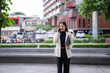 © Wasana - Smiling asian businesswoman walking and talking on mobile phone outdoors