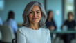© S.Jirut - Confident Senior Executive Woman with Silver Hair in White Blouse, Seated at Glass Conference Table During Business Meeting, Ultra-Detailed Corporate Photography