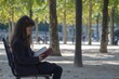 © Ifti Digital - Young girl engrossed in reading a book while seated in Tuileries garden surrounded by trees, Young girl reading a book on a chair in Tuileries park in Paris