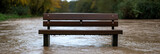 Park bench submerged in floodwater. Rising river levels render a bench useless. Environmental concerns and climate change concept.