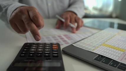 Poster - businessman uses a calculator and paperwork to analysis finances, investments, and tax reports at his desk calculator and digital tablet. business financial reports and data analysis