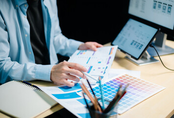 asian ux,ui designer reviewing app wireframes and color samples in modern office. creative process, 
