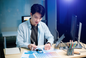 asian ux,ui designer reviewing app wireframes and color samples in modern office. creative process, 