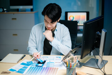 asian ux,ui designer reviewing app wireframes and color samples in modern office. creative process, 