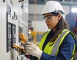 © Yelloone - A female technician wearing safety gear inspects electrical control panels using testing devices in an industrial setting.