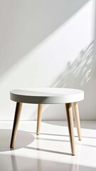 Wall Mural - white round side table with wooden legs casting shadows in bright sunlight against a white wall back