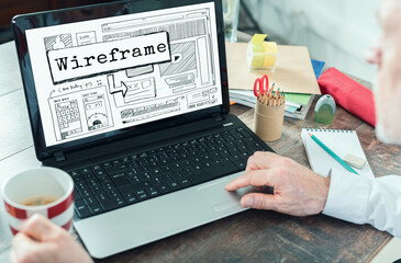 creative professional designs a wireframe layout on a laptop while enjoying coffee at a workspace