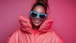 © Larisa AI - A cheerful woman wearing oversized sunglasses and a puffy coral jacket against a bright pink backdrop, radiating confidence and modern fashion trends in a fun atmosphere.