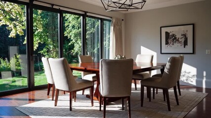 Poster - Elegant dining ambiance with sunlight streaming through large window, modern furniture, wooden table, upholstered chair