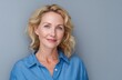 © AndyAziz - Blond woman in blue buttondown shirt smiles against grey background