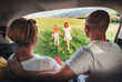 © Soloviova Liudmyla - Happy young couple watching two daughters sitting inside car trunk during road trip smiling and enjoying joyful family moment together expressing strong family values and love for traveling
