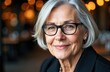 © starush - Close-up of a smiling elderly woman with gray hair and glasses in a warm, softly lit setting