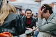© qunica.com - Group of friends sharing laughter and conversation at an outdoor cafe in a relaxed setting. The casual atmosphere highlights the joy and connection among the people enjoying each other's company.