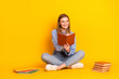 © deagreez - Young woman reading a book against a vibrant yellow background seeking educational inspiration