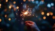 © Alex Piatkowski - Hand holding a sparkler at night with colorful bokeh lights in the background